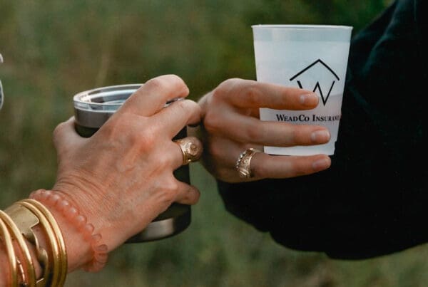 Homepage - two cups with company logos with a close up of their hands with grass behind them